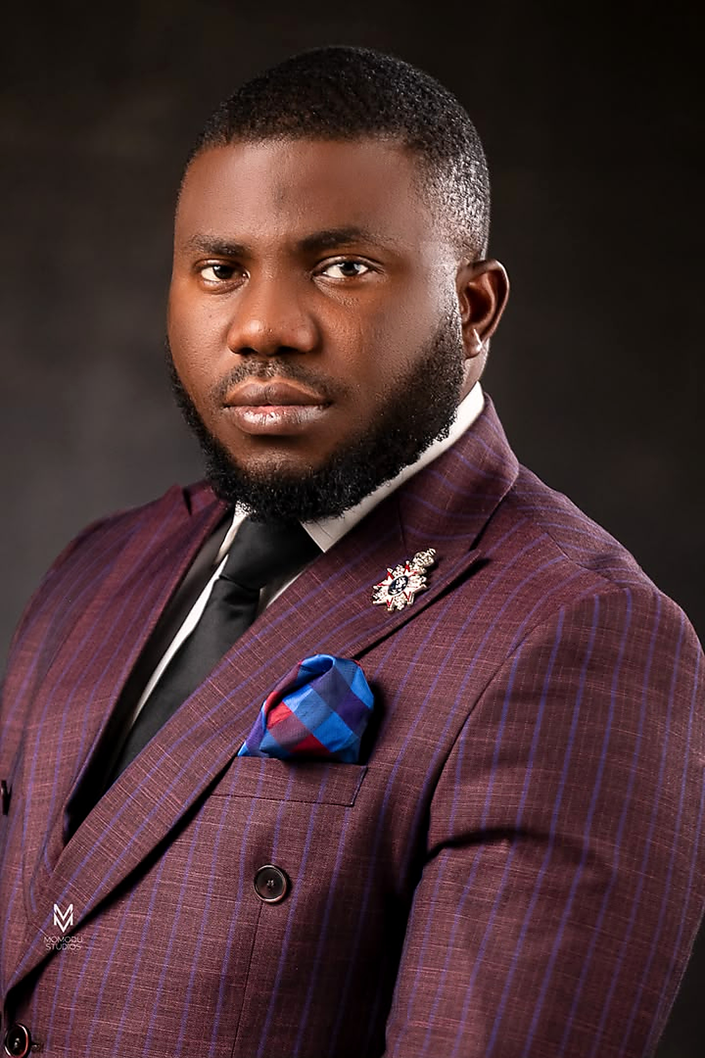 Bayonle Omoyele wearing a burgundy checked suit and blue pocket square.